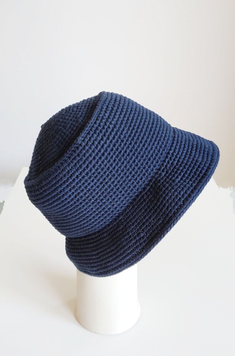 May include: A dark blue crocheted bucket hat. The hat is made of a thick, textured yarn and has a wide brim.