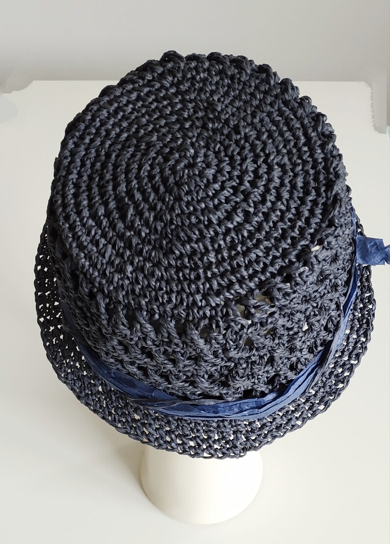 May include: A dark blue crocheted hat with a wide brim and a navy blue ribbon around the crown.