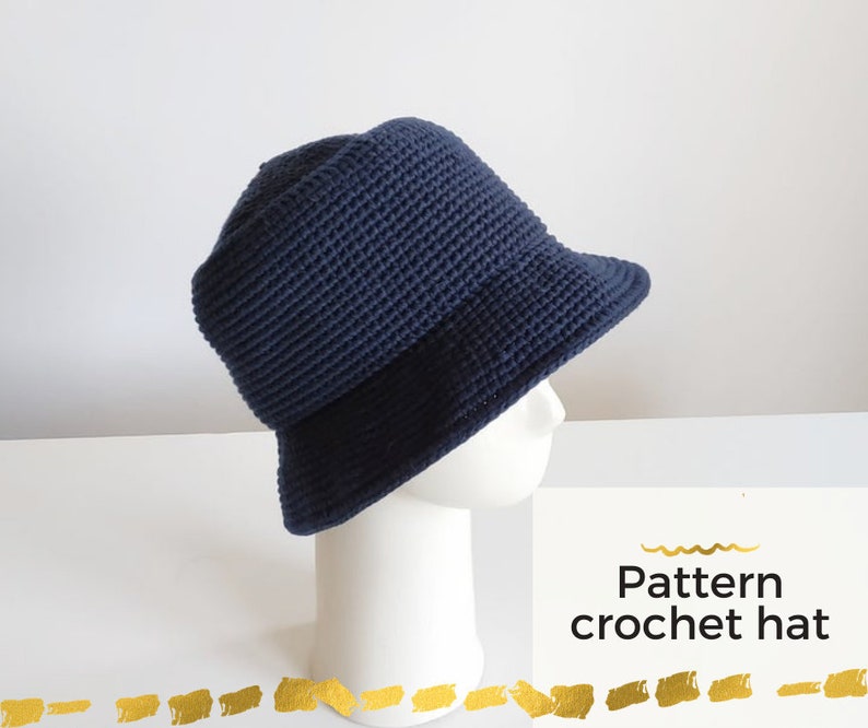 May include: A navy blue crochet bucket hat on a white mannequin head. The hat has a wide brim and a textured stitch pattern. The text "Pattern crochet hat" is visible below the hat.