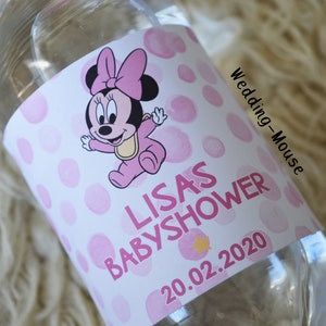 以下が含まれることがあります： ピンクと白のラベルが付いた透明なウォーターボトル。ラベルには、ベビーミニーマウスのデザインと「LISAS BABYSHOWER」の文字、日付「20.02.2020」が記載されています。ベビーシャワー向けにデザインされた、シンプルでクリーンなデザインのボトルです。