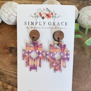 Puede incluir: Un par de pendientes de madera con un patrón geométrico en tonos de rosa, naranja y amarillo. Los pendientes están unidos a un poste de madera con un gancho de metal. Los pendientes están en una tarjeta blanca con el texto "SIMPLY GRACE by Dakota Country Designs" y "dakotacountrydesigns.etsy.com".