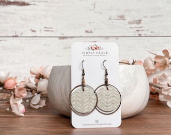 Puede incluir: Un par de pendientes de corcho con un patrón de chevron blanco. Los pendientes están en una tarjeta blanca con el texto "Simply Grace by Dakota Country Designs" y la dirección del sitio web "dakotacountrydesigns.etsy.com".