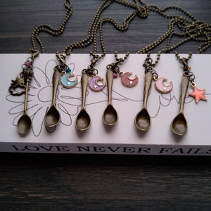 May include: Seven bronze spoon necklaces with enamel moon and star charms. The charms are in shades of blue, purple, pink, and orange.