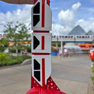 May include: A red and white monorail charm with black windows. The charm is attached to a red polka dot bag.