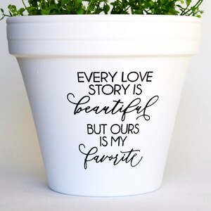 May include: White ceramic planter with black text that reads "Every love story is beautiful but ours is my favorite".