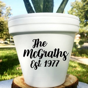 May include: White ceramic planter with black text that reads "The McGraths Est. 1977". A green succulent plant is growing in the planter.