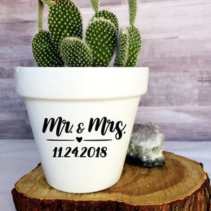May include: White ceramic planter with a cactus plant and the text "Mr. & Mrs. 11.24.2018" in black lettering.