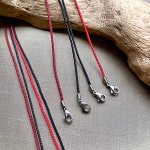 May include: Five cords with silver clasps. Two cords are red and three cords are black.