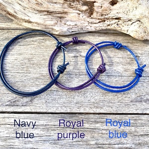 May include: Three leather bracelets in navy blue, royal purple, and royal blue. Each bracelet has a knotted design.