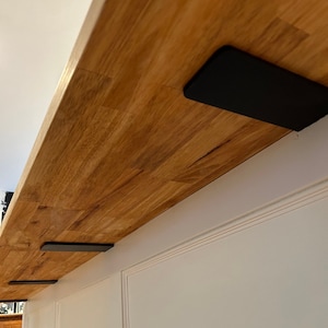 May include: A wooden countertop with black metal brackets attached to the underside. The brackets are used to support the countertop.