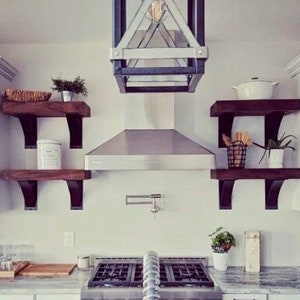 May include: A modern kitchen with white cabinets, stainless steel appliances, and a farmhouse style with wooden shelves and black metal brackets.