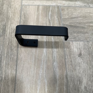 Sleek black bathroom fixture. Modern toilet paper holder