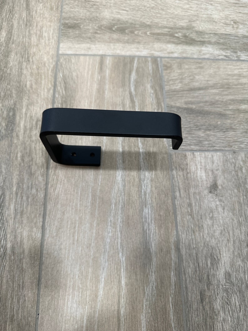 Sleek black bathroom fixture. Modern toilet paper holder