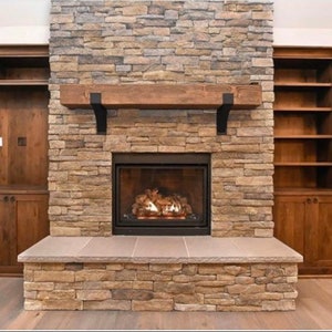 Metal Fireplace Mantel Brackets Mounted to Rustic Stone. Set of steel mantel brackets with powder coat finish in black, copper, and clear options
