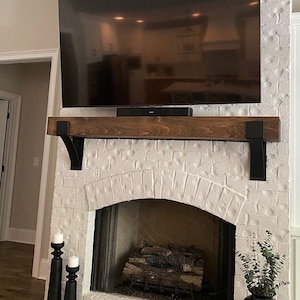 Artisan-made metal corbel with 4-inch lip, drilled holes for mounting, displayed on white wall. Wood Mantel on Spanish Style Fireplace.