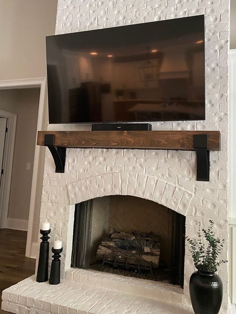 Artisan-made metal corbel with 4-inch lip, drilled holes for mounting, displayed on white wall. Wood Mantel on Spanish Style Fireplace.