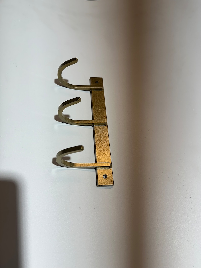May include: Gold metal wall mounted hook rack with three hooks.
