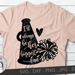 May include: A light pink t-shirt featuring a black cheerleader megaphone design with the words "I'll always be her biggest fan" and a heart. The design includes a pom-pom and is suitable for cheerleading fans.