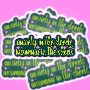 May include: A rectangular sticker with a dark green background and a white border. The text reads anxiety in the streets insomnia in the sheets in a yellow cursive font. Small pink four-pointed stars are scattered around the yellow lettering.