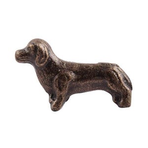 May include: A cast iron dachshund figurine in a bronze finish. The figurine is standing on all four legs with its tail curled up.