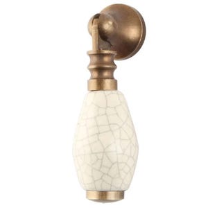 May include: White ceramic cabinet knob with a crackled glaze finish and a brass base.