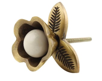 May include: A decorative brass flower-shaped cabinet knob with a white, spherical center. The knob features detailed leaf-like engravings on the petals and a threaded screw for installation. The overall design is vintage-inspired.