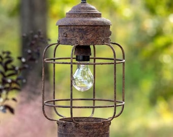 May include: A rustic, caged pendant light with a weathered metal finish. The light features a clear glass bulb and a wire cage.