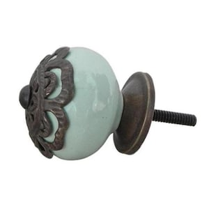 May include: A light blue ceramic cabinet knob with a decorative metal trim. The knob has a screw-on base.