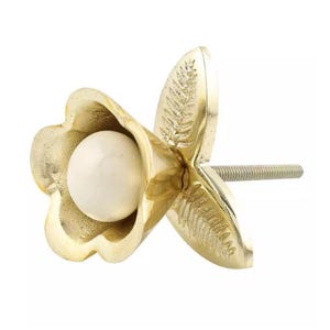 May include: A decorative cabinet knob with a gold finish, shaped like a flower with a white pearl center. The knob has a threaded screw for easy installation. The flower petals have a detailed leaf pattern.