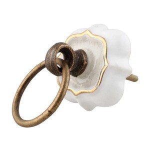 May include: White ceramic cabinet knob with a gold trim and a ring pull. The ring pull is made of brass and has a rustic finish.