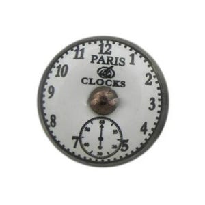 May include: A white porcelain clock face with black numbers and hands. The clock face has the text "PARIS CLOCKS" in black lettering.
