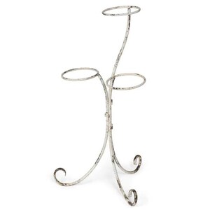 May include: White metal plant stand with three tiers. The stand has a distressed finish and a decorative scroll design.
