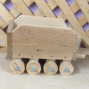 May include: A wooden toy wagon with a rectangular bed and four wheels. The wagon is made of natural wood and has a rustic look.