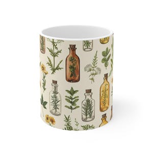 May include: White ceramic mug with a pattern of various herbs and plants in glass bottles. The bottles are filled with different colored liquids and have cork stoppers.