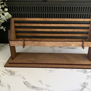 May include: A wooden bench with a slatted back and a shelf underneath. The bench is made of dark brown wood and has a natural wood finish.