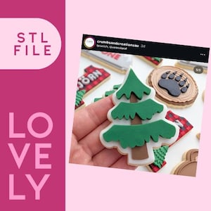 Pode incluir: Uma mão segura um biscoito em forma de árvore de Natal verde e marrom com glacê branco. Outros biscoitos no fundo incluem uma pata de urso, uma cara de urso e um design xadrez vermelho e preto. As palavras "STL FILE" e "LOVELY" são visíveis.