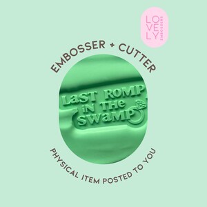 May include: A light green cookie embosser and cutter featuring the raised text 'LAST ROMP IN THE SWAMP' accompanied by a small diamond ring icon. The tool is designed for creating impressions in dough, with the text and icon clearly visible.