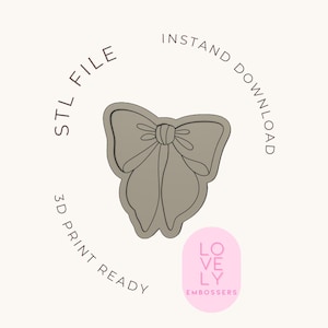 Peut inclure: Un fichier STL en forme de nœud papillon gris, prêt pour l'impression 3D. Le design est souligné en noir et comporte le texte "STL FILE", "INSTANT DOWNLOAD" et "3D PRINT READY". Un ovale rose avec "LOVELY EMBOSSERS" est en bas à droite.