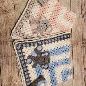 May include: Two crocheted baby blankets with matching hats. One blanket is pink and white with a gray elephant applique. The other blanket is blue and white with a gray elephant applique.