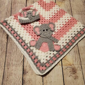 May include: A pink and white crocheted baby blanket with a gray elephant applique and a matching crocheted hat.