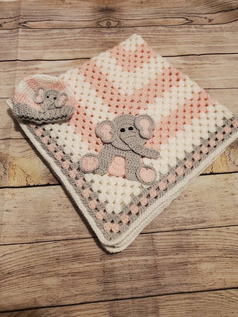 May include: A pink and white crocheted baby blanket with a gray crocheted elephant applique and a matching gray crocheted elephant hat.