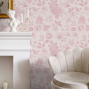 May include: A room featuring a floral wallpaper with a light pink background and pink flower and leaf patterns. A white fireplace, a bust statue, and a gold-framed mirror are visible. A cream-colored, scalloped-back chair is in the foreground.
