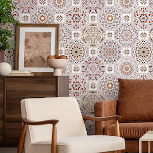 May include: A living room interior with a white armchair and a brown leather sofa. The wall is covered with a patterned wallpaper featuring a geometric design in shades of red, blue, and white.
