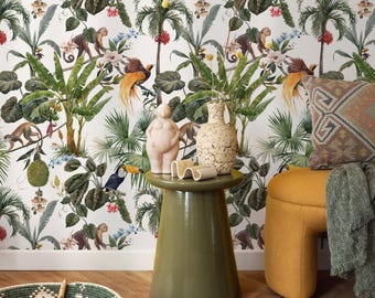May include: A vibrant interior scene featuring a green side table with decorative items, including a pink figurine and a textured vase. The background showcases a tropical wallpaper with monkeys, toucans, and lush foliage. A yellow ottoman and patterned pillow add color.