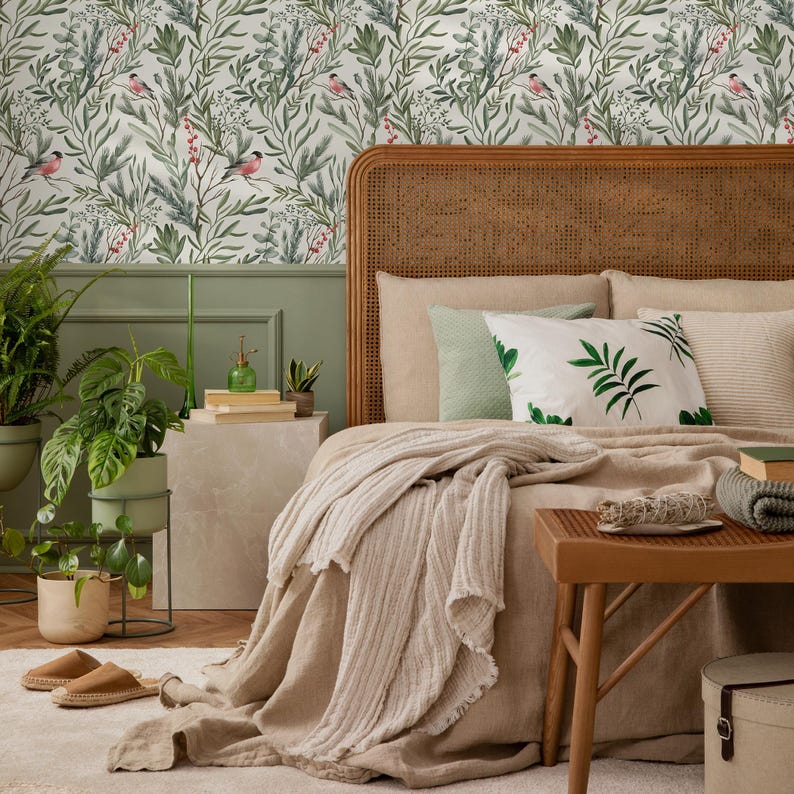 Op de afbeelding: Een slaapkamer met een bed met een beige hoofdeinde, een beige deken en een beige kussen met groene bladeren. Het bed staat tegen een muur met een groen-wit behang met vogels en bladeren.