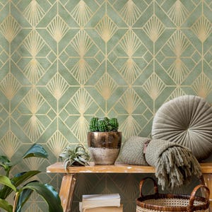 May include: Sage green wallpaper with a gold geometric art deco pattern. A wooden shelf displays a potted cactus, a small succulent, a woven basket, and a gray round pillow. A green blanket and a round pillow are also on the shelf.