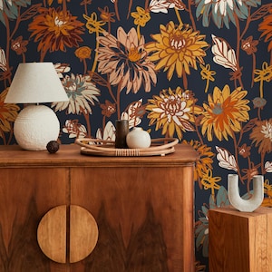 Könnte beinhalten: Innenraum mit einem Holzschrank, einer runden Lampe und einem dekorativen Tablett. Der Hintergrund ist eine florale Tapete mit dunkelblauem Grund und großen Blumen in Orange, Gelb und Weiß. Der Schrank hat runde Holzgriffe.