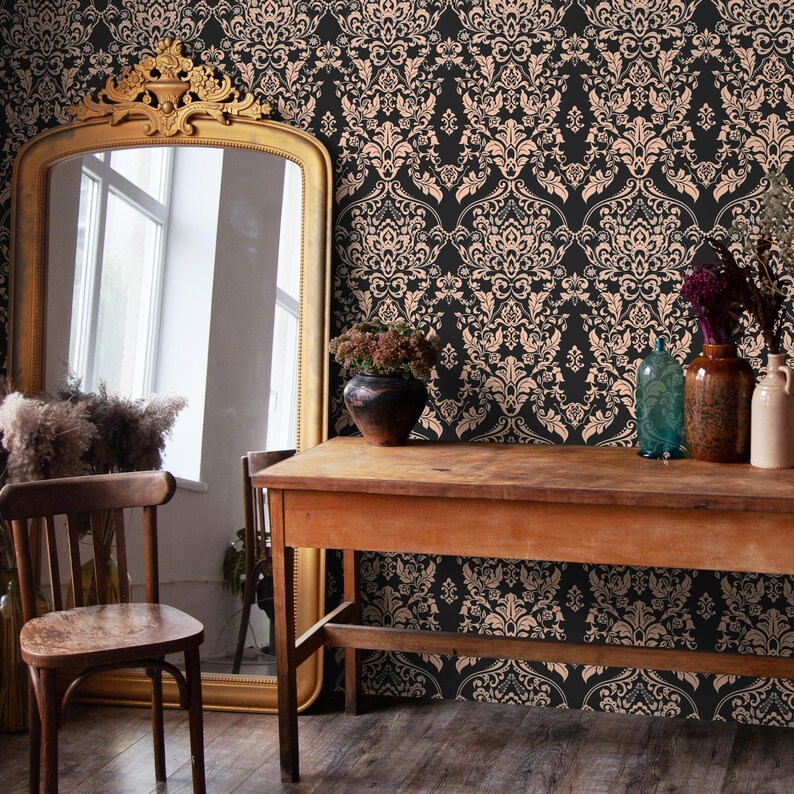 May include: A black and peach damask wallpaper pattern with a gold framed mirror, a wooden table, and a chair in the foreground.