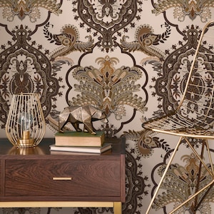 May include: A dark wood nightstand with a gold-colored metal frame, a decorative gold wire lamp, and a geometric bear sculpture. The background features a beige and brown paisley wallpaper, and a gold wire chair.