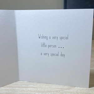 May include: A white card with black text that reads "Wishing a very special little person... a very special day."